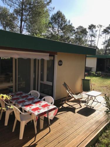 eine Terrasse mit Tisch und Stühlen auf einem Deck in der Unterkunft Village Vacances aux Villages sous les Pins in Léon