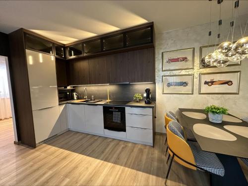 a kitchen with white cabinets and a table with chairs at Apartmán Maťko in Levice