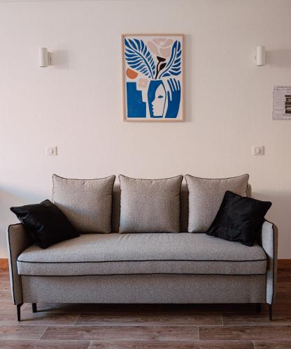 a couch in a living room with a painting on the wall at Mage hôtels - HÔTEL LA GRENETTE in Roanne