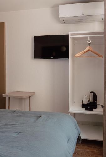 a bedroom with a bed and a tv on the wall at Mage hôtels - HÔTEL LA GRENETTE in Roanne