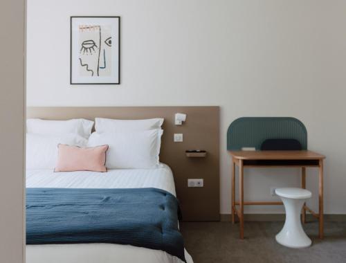 a bedroom with a bed and a table and a chair at Mage hôtels - HÔTEL LA GRENETTE in Roanne