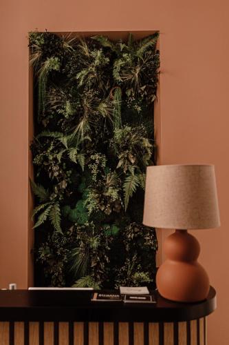 a lamp on a table next to a plant wall at Mage hôtels - HÔTEL LA GRENETTE in Roanne