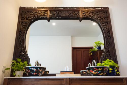a mirror on a counter with two sinks in a bathroom at Khmer Surin Boutique Guesthouse in Phnom Penh