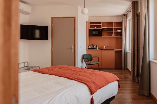 ロアンヌにあるMage hôtels - Hôtel la grenetteのベッドとキッチン付きのホテルルーム
