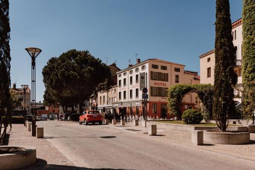 a city street with a red car driving down the street at Mage hôtels - HÔTEL LA GRENETTE in Roanne