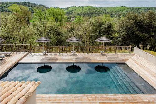 a pool with umbrellas and a view of the mountains at La maison des collines in Allemagne-en-Provence
