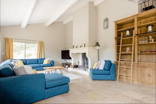 a living room with two blue couches and a fireplace at La maison des collines in Allemagne-en-Provence