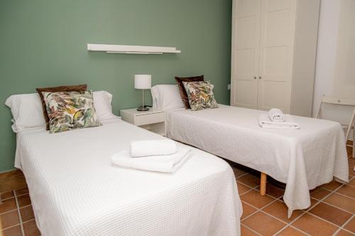 a room with two beds with white sheets at Apartamentos Casa Tuli A, ALJARAQUE in Aljaraque