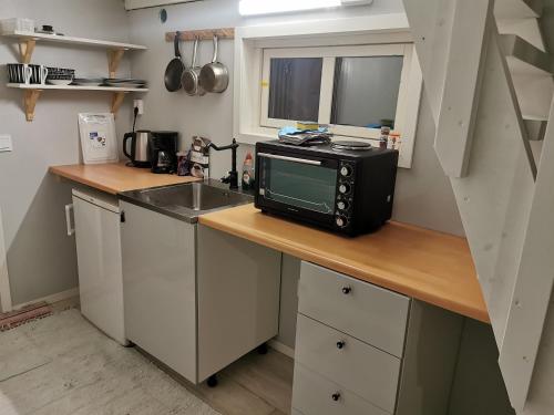 una pequeña cocina con microondas y fregadero en Lilla stugan, en Gotemburgo