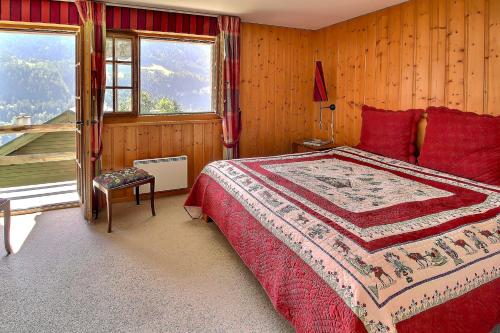 a bedroom with a bed with red pillows and a window at Triplex Overlooking The Village - Terrace & Bbq in Champéry