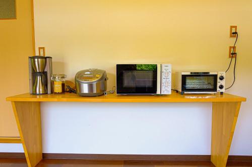 a table with a microwave and a coffee maker on it at 四万十川まで歩いて行ける 一棟まるっと貸し切りの宿 gu in Shimanto