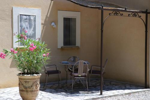 a patio with a table and chairs and a plant at LA VILLA DU PETIT BOIS Les Lavandes in Faucon