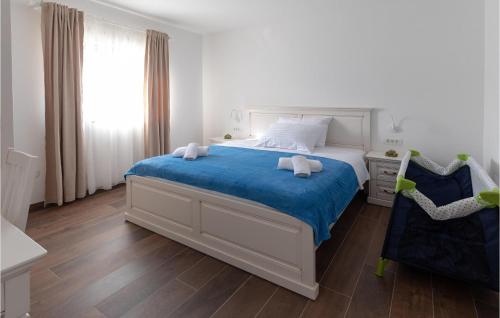Schlafzimmer mit einem Bett mit blauer Bettwäsche und einem Fenster in der Unterkunft Nice Home In Klek With Wifi in Klek