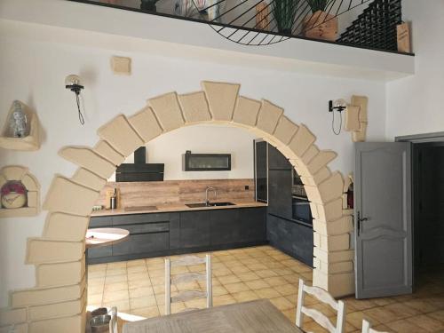 une cuisine avec une arche, une table et des chaises dans l'établissement La Maison de Léonie sur Vias, à Vias