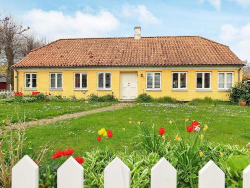 uma casa amarela com uma cerca branca e flores em 11 person holiday home in r sk bing em Aeroskobing