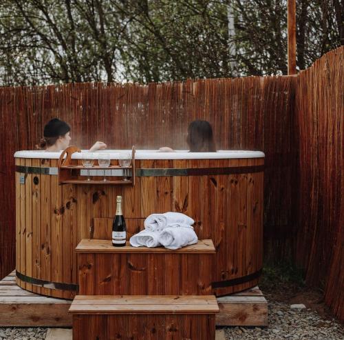two people in a hot tub with a bottle of wine at Glamping Biała Czapla z balią nad jeziorem czorsztyńskim in Maniowy