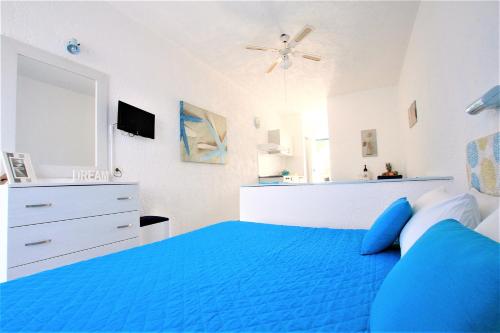 a bedroom with a blue bed and a ceiling fan at Christiana Hotel Apartments in Gennadi