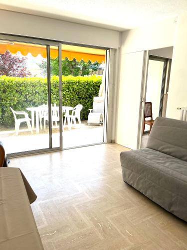 un salon avec un canapé et une terrasse dans l'établissement Appartement Cosy Piscine Mandelieu, à Mandelieu-la-Napoule