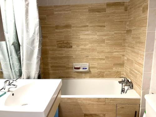 une salle de bain avec une baignoire blanche et un lavabo dans l'établissement Appartement Cosy Piscine Mandelieu, à Mandelieu-la-Napoule