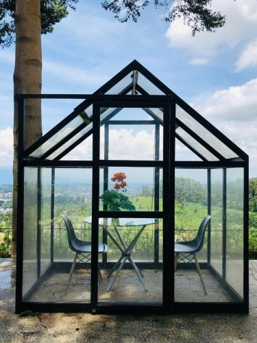 a glass house with two chairs and a table at De Pointé Resort & Resto in Campaka