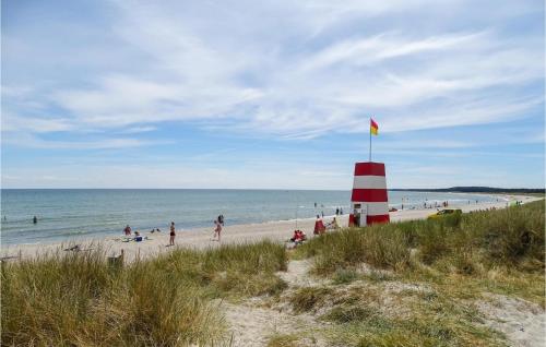 a group of people on a beach with a red and white lighthouse at Holiday Home Aspevej Grenaa X in Grenå