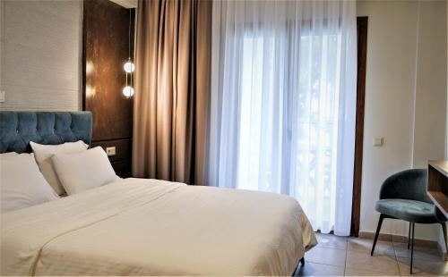 a bedroom with a bed and a chair and a window at Country Inn in Kallithea Halkidikis