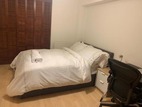 a bedroom with a bed with white sheets and a chair at Lovely room, free parking in private gated place in London
