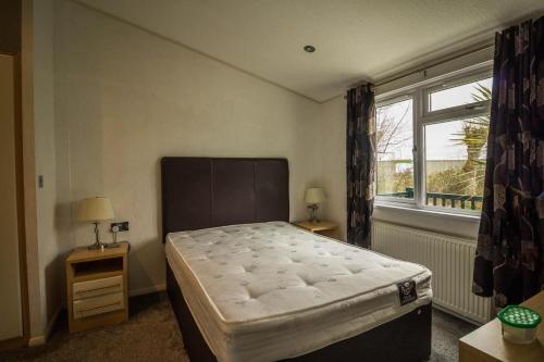 Un dormitorio con una cama grande y una ventana en Modern 4 Berth Lodge With Decking At Manor Park In Hunstanton Ref 23024w, en Hunstanton