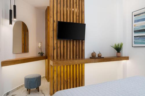 a bedroom with a wooden partition with a television on it at Amera Suites in Fira