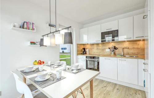 eine Küche mit weißen Schränken und einem Esstisch in der Unterkunft Nice Home In Tossens With Wifi in Tossenserdeich