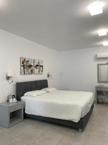 a white bedroom with a bed and a table at Anemoni Beach Hotel in Skiathos Town