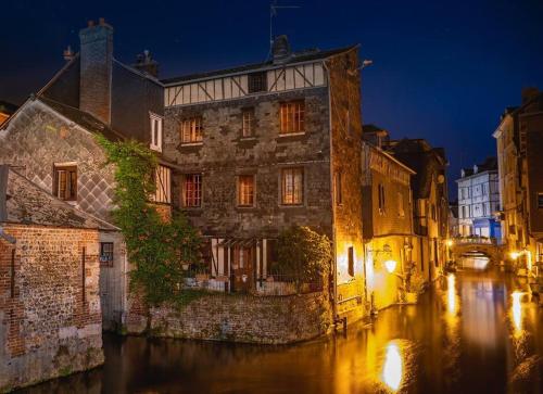 un viejo edificio en un canal por la noche en Suites Carnot, Venise Normande., en Pont-Audemer