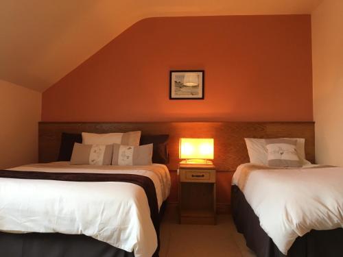 2 Betten in einem Hotelzimmer mit einer Lampe auf einem Tisch in der Unterkunft The Clady in Bunbeg