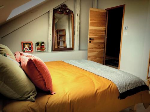 ein Schlafzimmer mit einem Bett mit Kissen und einem Spiegel in der Unterkunft Maison Puchouaou Chambres d'Hôtes sur le chemin de Saint jacques de Compostelle in Montesquiou