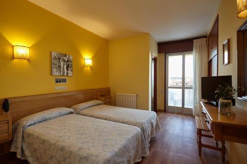 a bedroom with a bed and a desk and a television at Hotel Con D´Arbon in A Lanzada