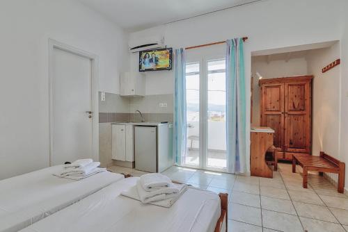 a room with two beds and a kitchen with a window at Pavlos Place in Antiparos Town