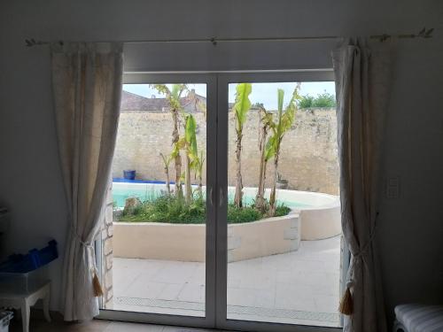 d'une porte coulissante en verre avec vue sur la piscine. dans l'établissement Maison Althea Rosea - 3 chambres et piscine, à Nieulle-sur-Seudre