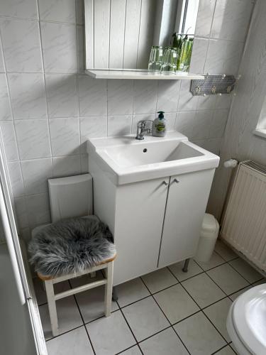 a white bathroom with a sink and a stool at Gästehaus in Senzig