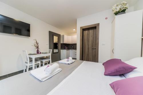 una camera da letto con un grande letto bianco con cuscini viola di Studio Apartment Kastel Star a Kaštela (Castelli)