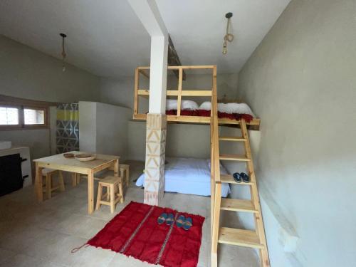 Etagenbett in einem Zimmer mit einem Tisch und einer Leiter in der Unterkunft Issouganes N Toubkal Maison d hôtes in Oussertek