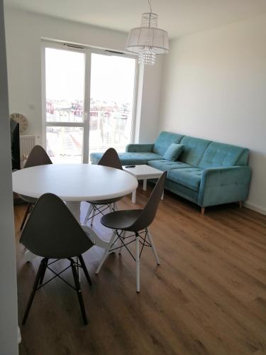 a living room with a blue couch and a table and chairs at Nowy w centrum 2 in Giżycko