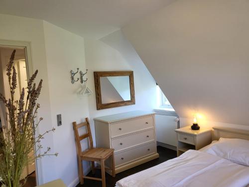 een slaapkamer met een bed, een spiegel en een stoel bij Ferienwohnung Mühlenhof 7 in Sankt Peter-Ording
