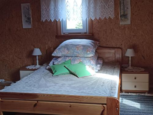 Zielona Dolina في Lewkowo: سرير مع وسادتين خضراء ونافذة