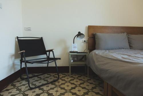 a bedroom with a chair next to a bed at 鴉埠客棧x南華大旅社 in Hou-hsi