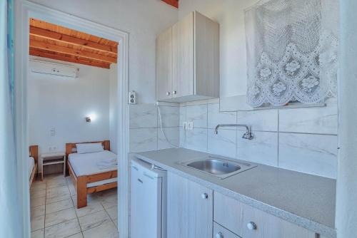 a white kitchen with a sink and a table at Pavlos Place in Antiparos Town