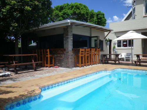 a swimming pool in front of a house at Hermanus Backpackers & Budget Accommodation in Hermanus