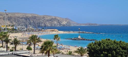 a beach with palm trees and people in the water at Torres del Sol-La Perla ocean view in Los Cristianos