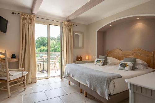 a bedroom with a large bed and a balcony at Hotel Les Messugues in Saint Paul de Vence