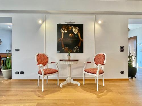 twee stoelen en een tafel in een kamer met een schilderij bij HOLIDAY HOUSE VILLA CAMILLA Luxury Apartment in Perugia
