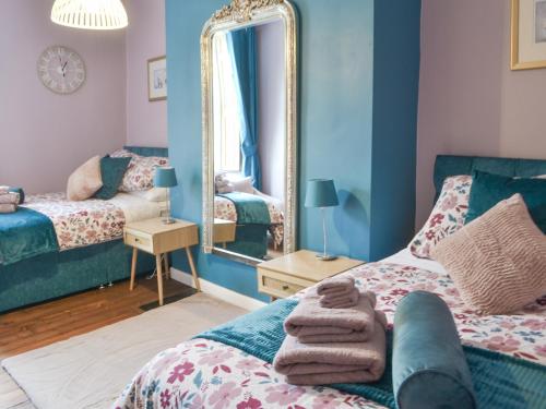 um quarto azul com uma cama e um espelho em Baekere House Apartment em Alnwick